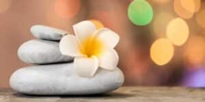 Achtsamkeits-Adventskalender: Zen-Steine mit Blüte vor warmen Lichtern