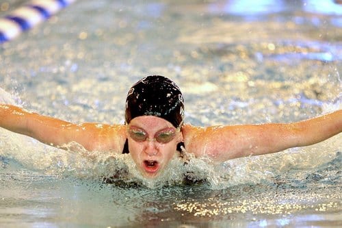 Kalorien beim Schwimmen: Schwimmerin beim Delfinschwimmen im Hallenbad