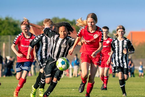 Jugendfußball: Mädchen und Jungen laufen bei einem Spiel dem Ball hinterher