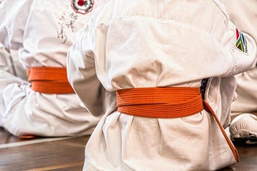 Gürtelfarben im Kampfsport: Karateka mit orangem Gürtel in weißen Anzügen