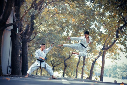 Karate als Geschenkidee: zwei Karateka mit schwarzem Gürtel, einer springt zu einem Tritt