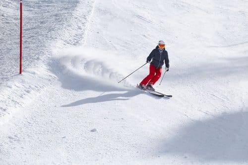 Skifahren und Kalorienverbrauch: Skifahrerin in roter Hose fährt einen Schwung auf der Piste