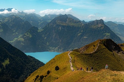 Wandern in den Alpen: Wanderweg auf einem Grat über einem türkisen Bergsee