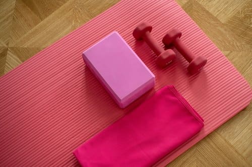 Yogamatte verschenken: pinke Matte mit Yogablock, Handtuch und kleinen Hanteln